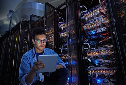 An IT technician is working on hospital network infrastructure check and monitoring data on a table device.