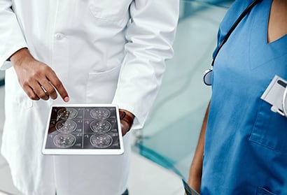 Two caregivers are discussing patient data generated by GE Healthcare EMR Integration system showing on a tablet device.